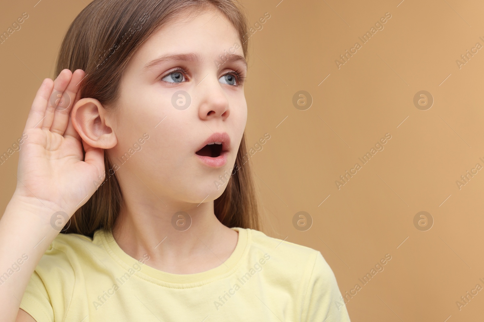 Photo of Little girl with hearing problem on pale brown background, space for text