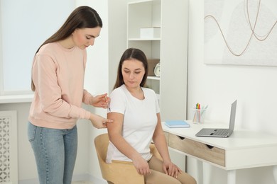 Woman giving insulin injection to her diabetic friend at home
