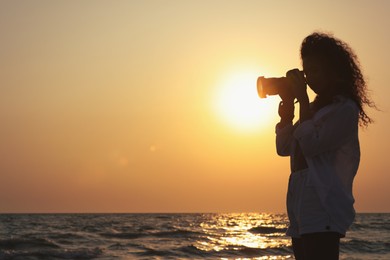 Photo of Photographer taking photo of sea with professional camera at sunset