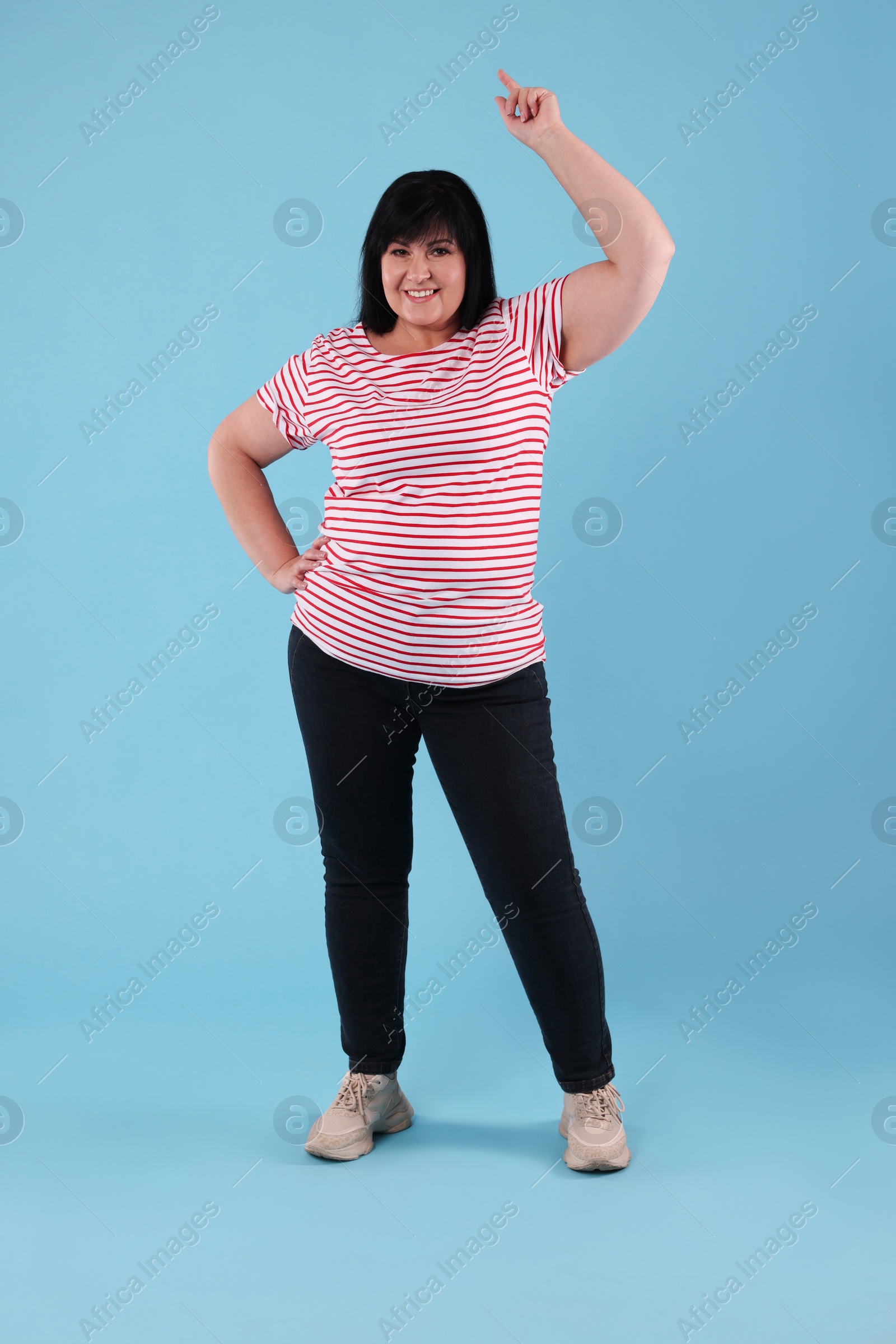 Photo of Beautiful overweight mature woman with charming smile on turquoise background 