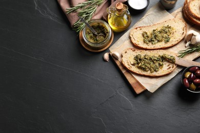 Photo of Tasty bruschettas with pesto on black table, flat lay. Space for text