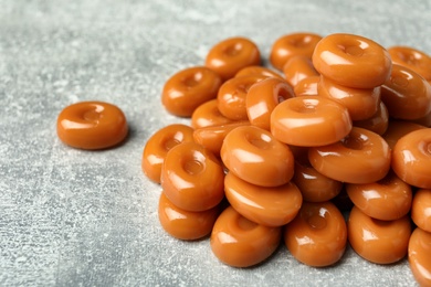Photo of Tasty hard toffee candies on light grey table, closeup
