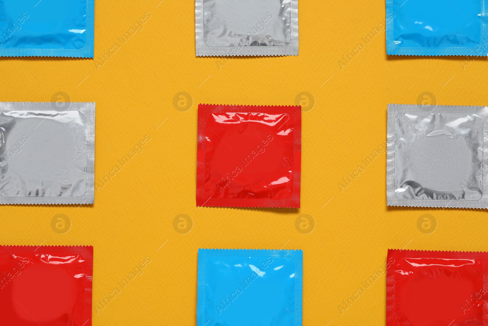 Photo of Condom packages on orange background, flat lay. Safe sex