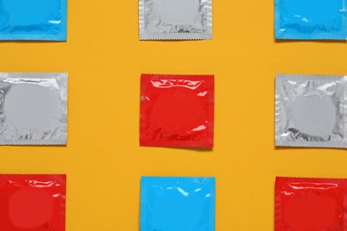 Condom packages on orange background, flat lay. Safe sex