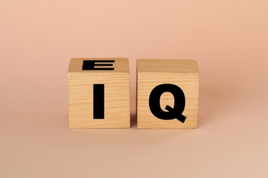 Wooden cubes with abbreviation IQ on beige background
