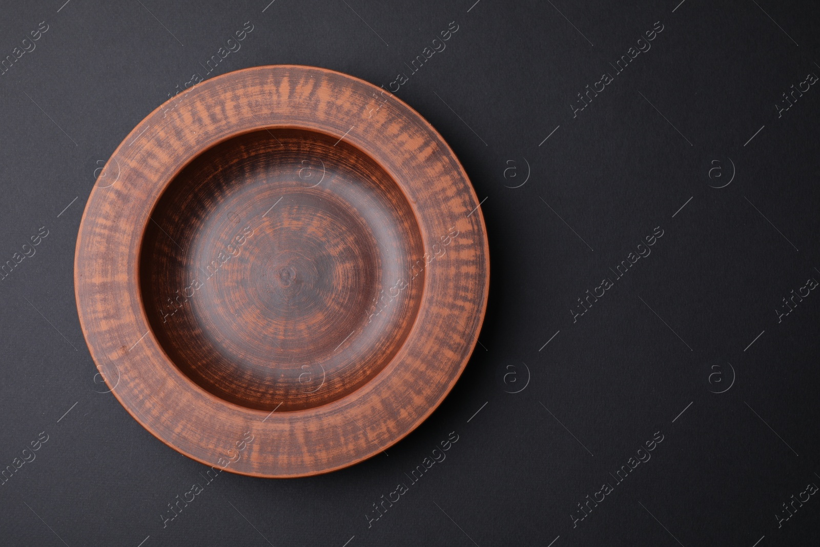 Photo of Ceramic bowl on black background, top view. Space for text