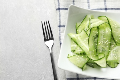 Photo of Plate with delicious cucumber salad served on grey table, top view. Space for text