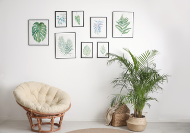 Beautiful paintings of tropical leaves on white wall in living room interior