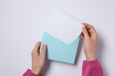 Photo of Woman taking card out of letter envelope at pink table, top view. Space for text