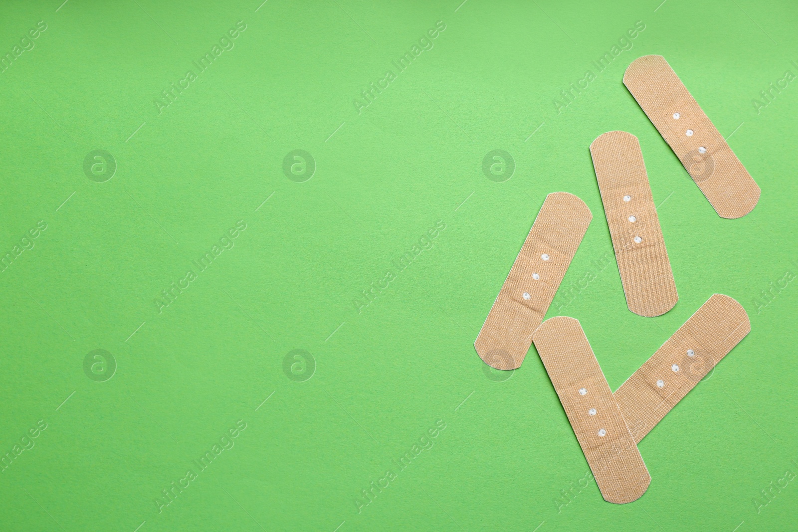 Photo of Sticking plasters on green background, flat lay. Space for text