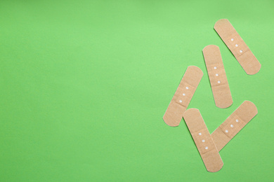 Photo of Sticking plasters on green background, flat lay. Space for text