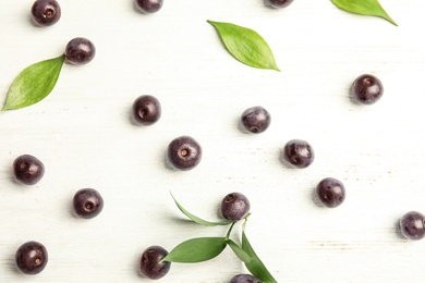 Flat lay composition with fresh acai berries and leaves on wooden background