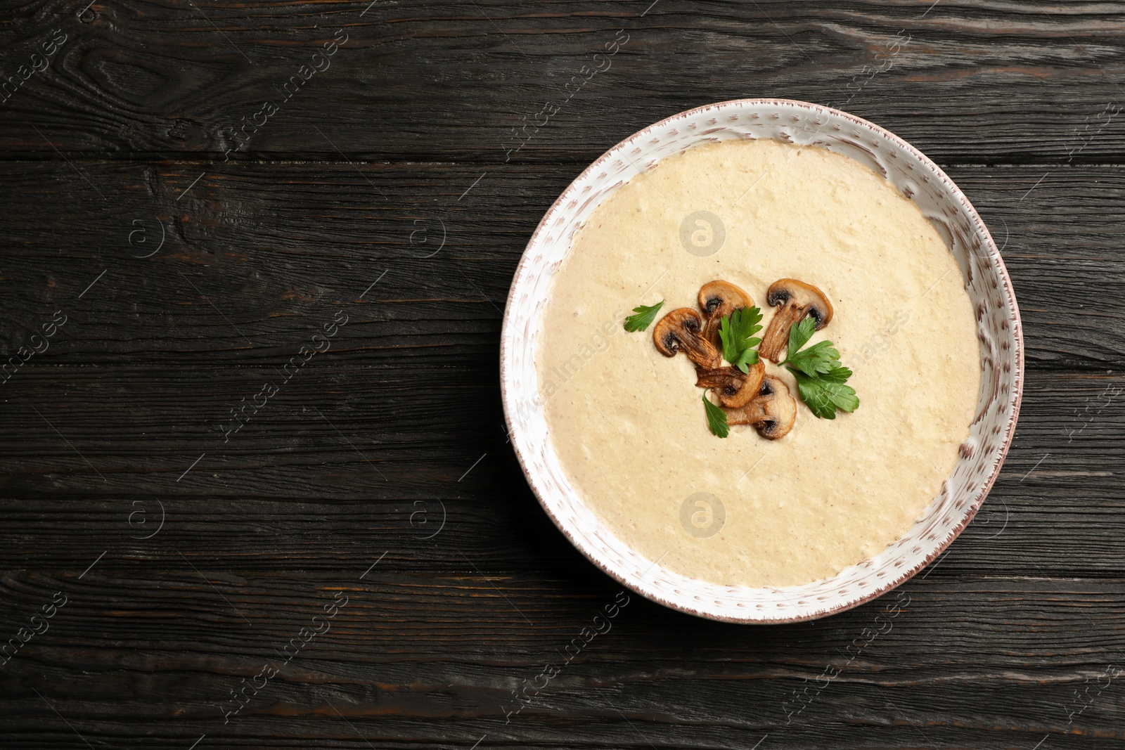 Photo of Bowl of fresh homemade mushroom soup on wooden background, top view with space for text