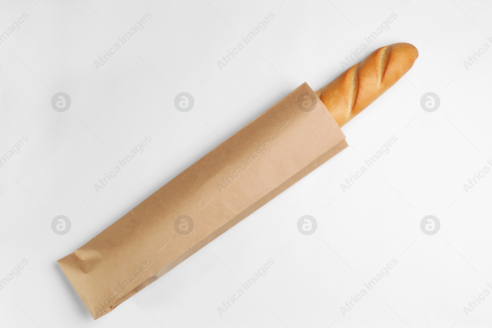 Photo of Paper bag with baguette on white background, top view. Space for design