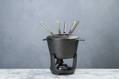 Fondue set on white marble table against light grey background