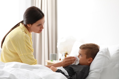 Mother taking care of her little son suffering from cold in bed