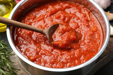 Photo of Homemade tomato sauce and spoon in pot on table, closeup