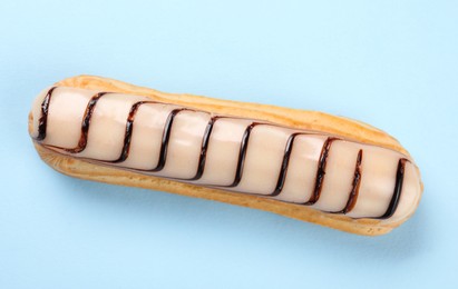 Photo of Delicious eclair covered with glaze on light blue background, top view