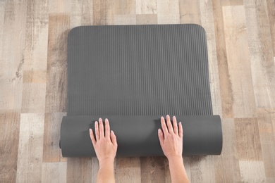 Photo of Woman rolling yoga mat on floor indoors, top view