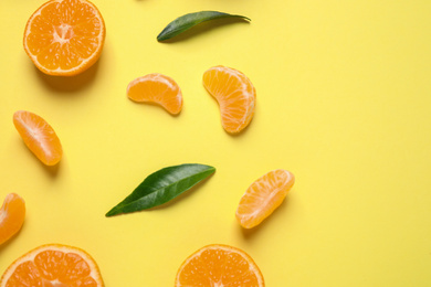 Flat lay composition with fresh ripe tangerines and leaves on light yellow background. Citrus fruit