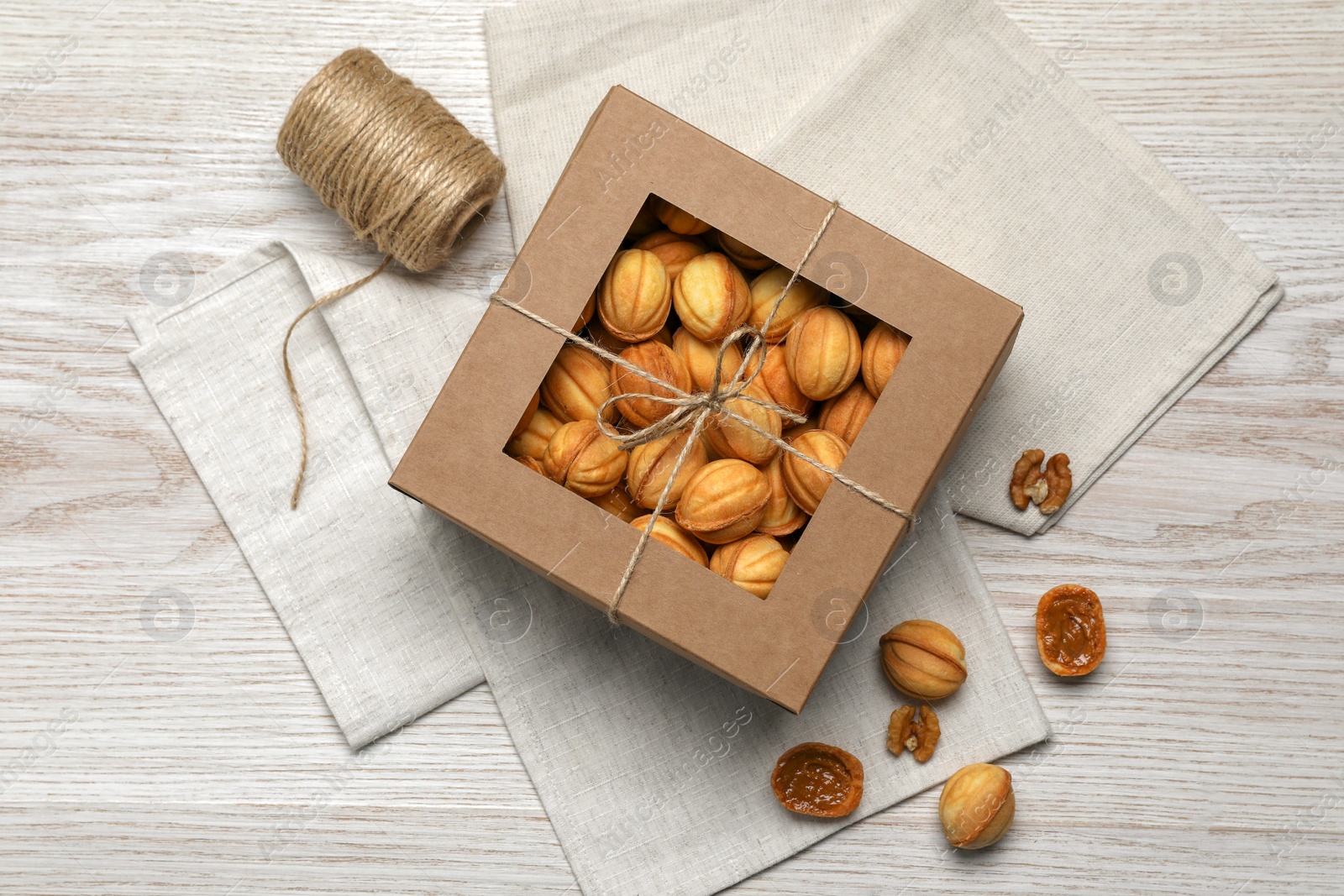 Photo of Delicious nut shaped cookies with boiled condensed milk in box on white wooden table, flat lay