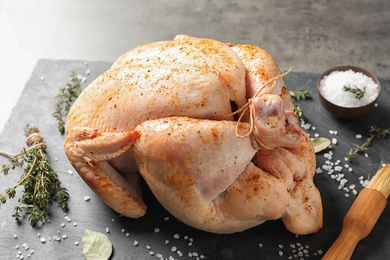 Photo of Slate plate with raw spiced turkey on table, closeup