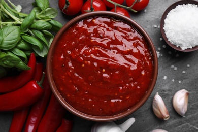 Photo of Bowl of chili sauce and ingredients on grey table, top view