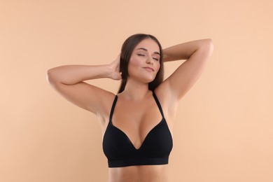 Photo of Portrait of young woman with beautiful breast on beige background