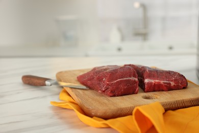 Photo of Board with beef meat and knife on white marble table indoors. Space for text