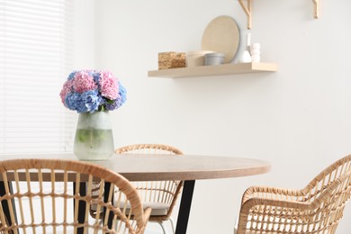 Vase with hydrangea flowers on wooden table in stylish dining room