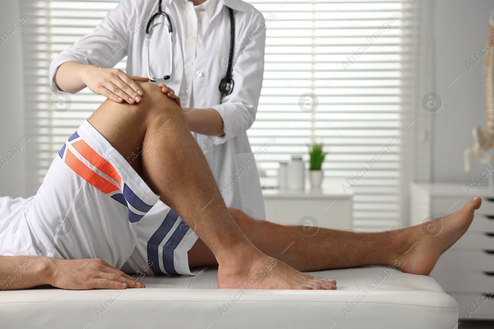 Photo of Sports injury. Doctor examining patient's knee in hospital, closeup