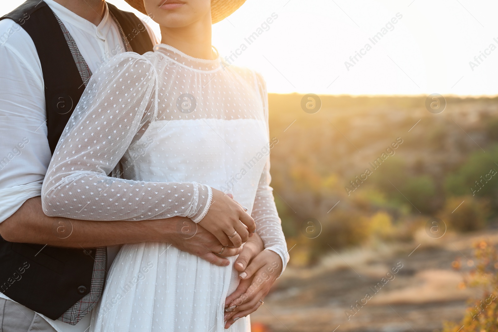 Photo of Happy bride and groom standing outdoors at sunset, closeup