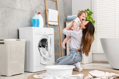 Photo of Mother with her daughter having fun while washing baby clothes in bathroom