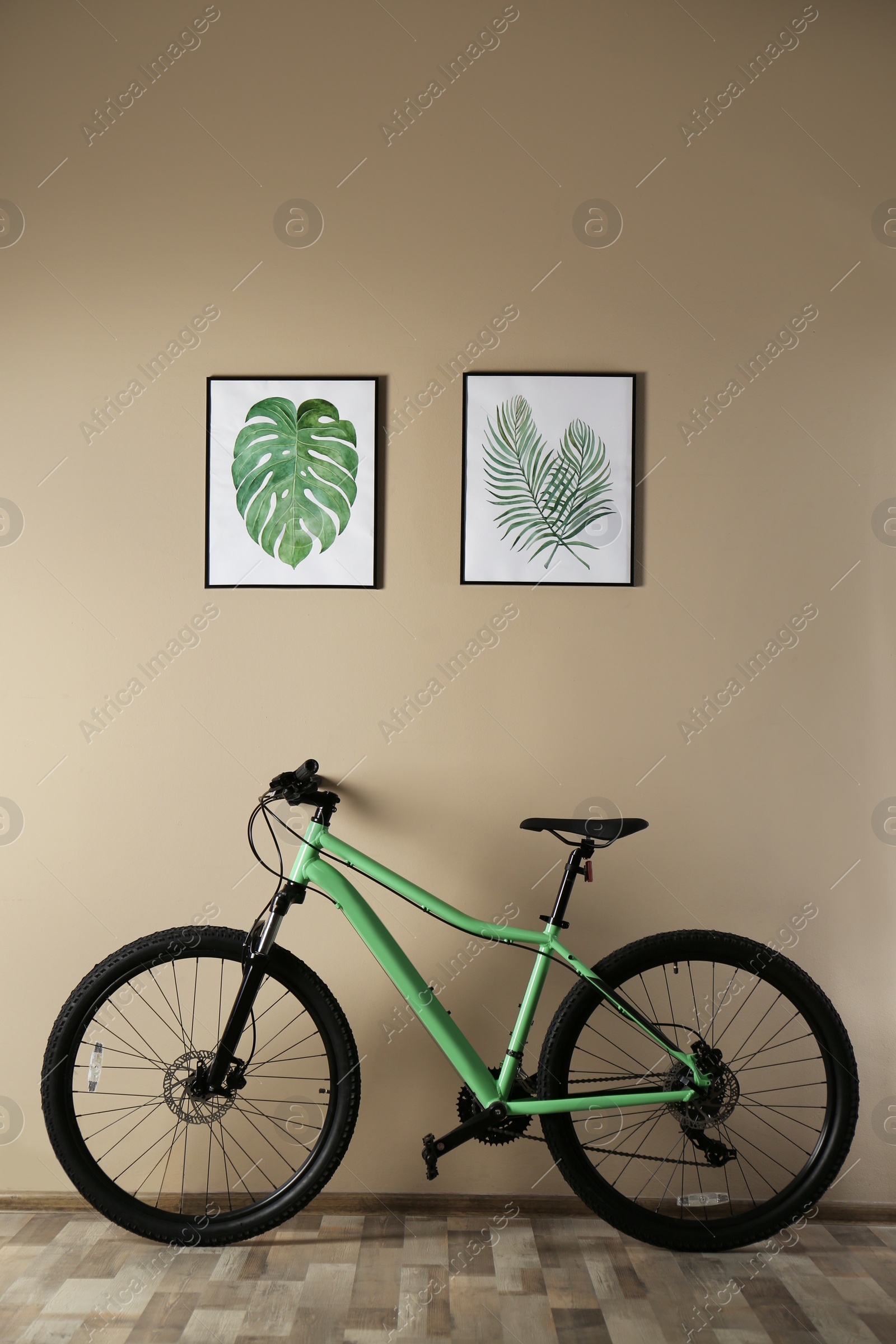 Photo of Modern green bicycle near beige wall indoors