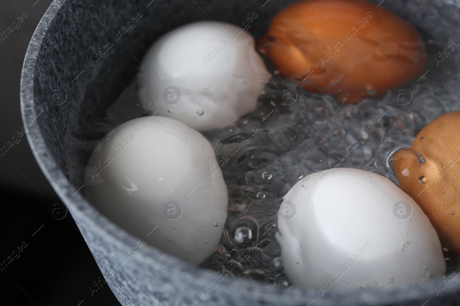 Photo of Chicken eggs boiling in saucepan, closeup view