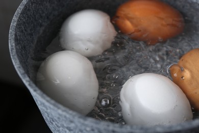 Chicken eggs boiling in saucepan, closeup view