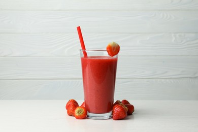 Photo of Glass with delicious berry smoothie and fresh strawberries on white wooden table