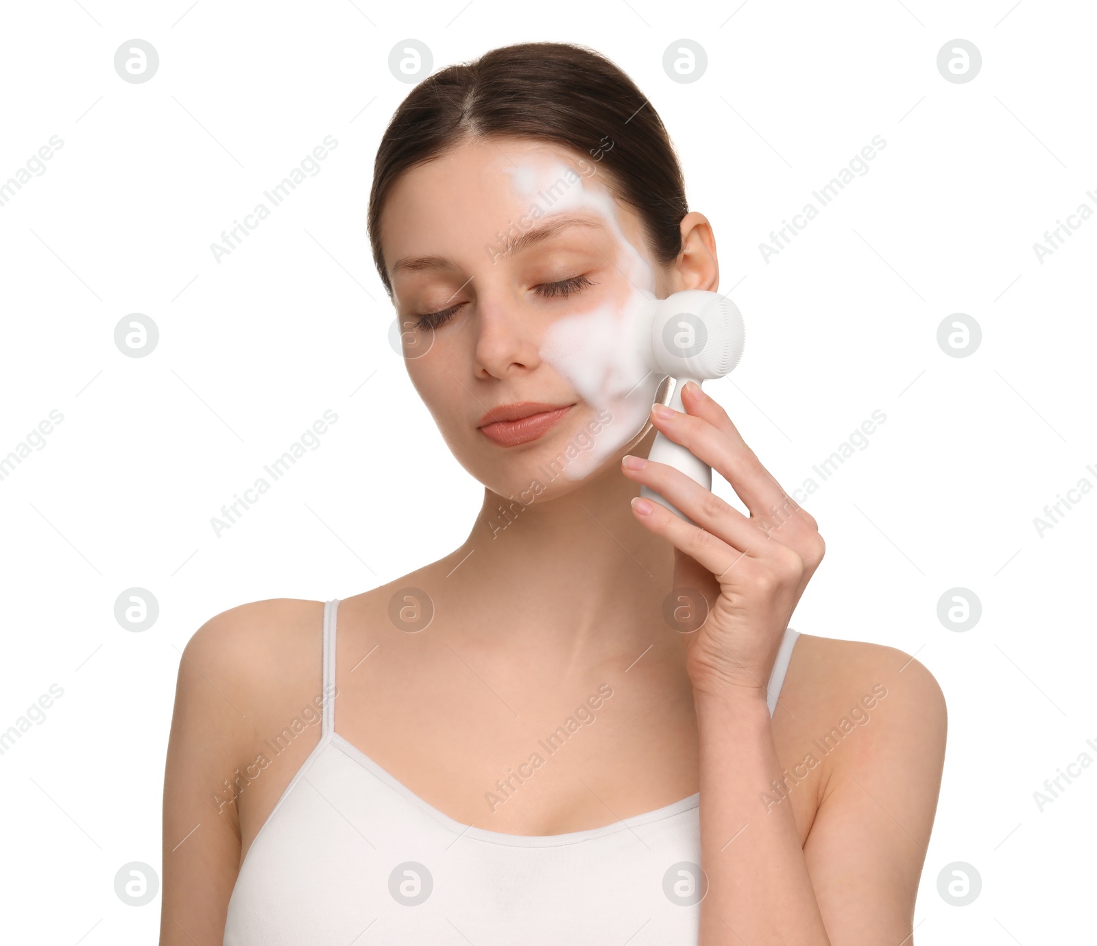 Photo of Young woman washing face with brush and cleansing foam on white background