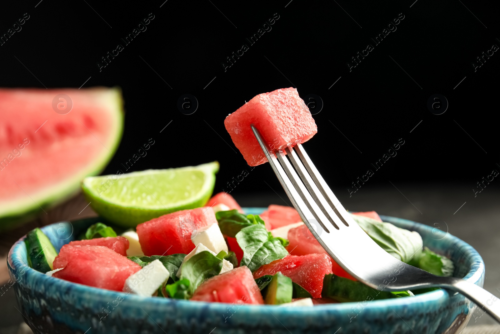 Photo of Delicious salad with watermelon served on black table, closeup