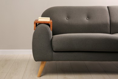 Photo of Book on sofa with wooden armrest table in room. Interior element