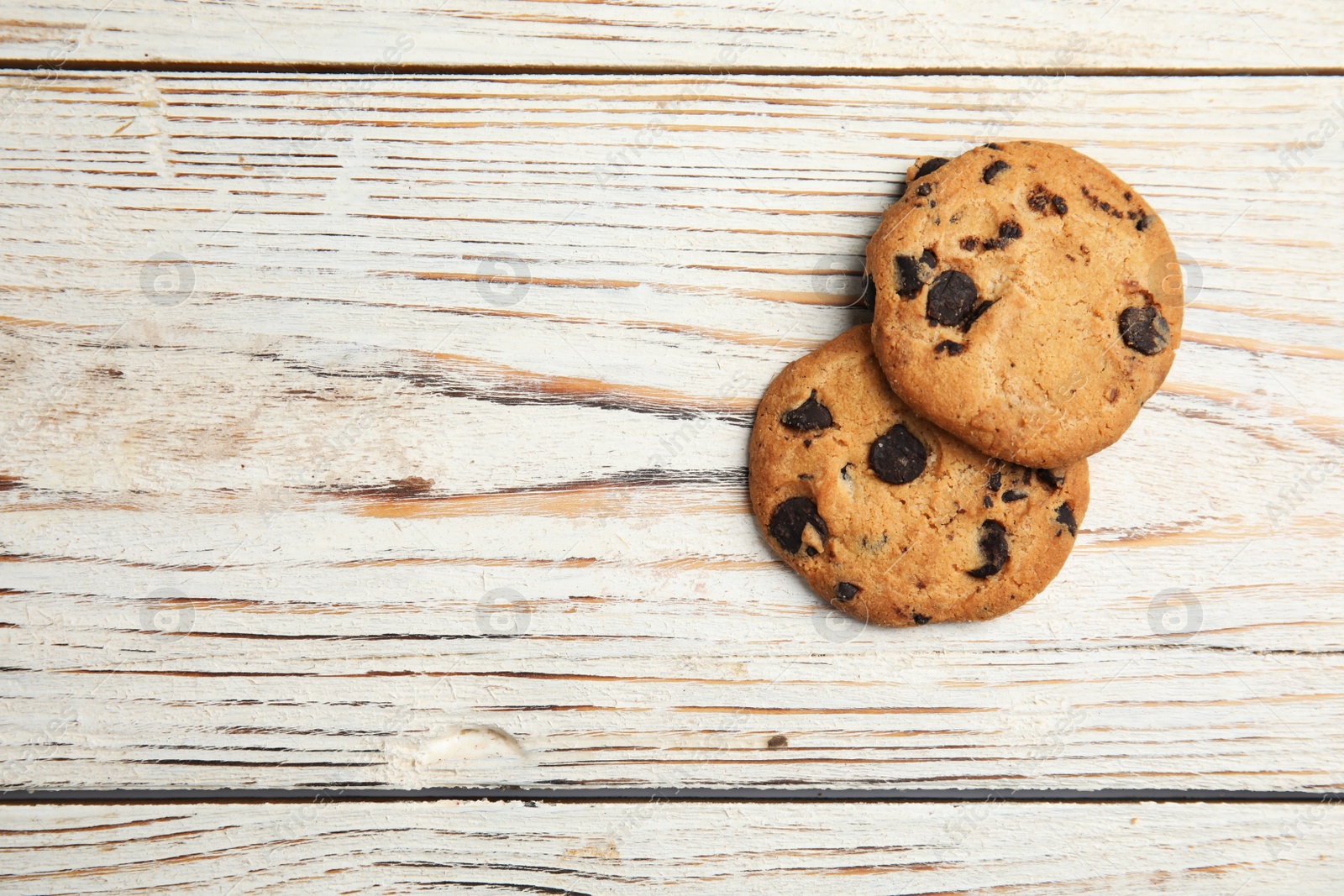 Photo of Delicious chocolate chip cookies on wooden table, flat lay. Space for text