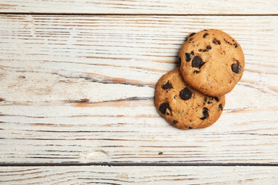 Delicious chocolate chip cookies on wooden table, flat lay. Space for text