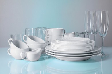 Set of clean dishes and glasses on light blue table