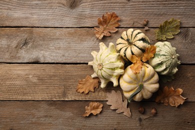 Photo of Fresh ripe pumpkins and dry leaves on wooden table, flat lay. Space for text