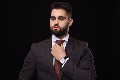 Photo of Handsome businessman in suit and necktie on black background