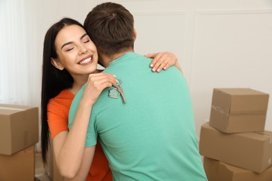 Photo of Happy young couple with key hugging in new house