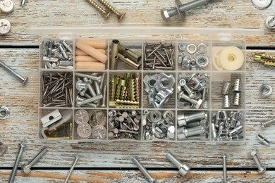 Organizer with many different fasteners on rustic wooden table, flat lay