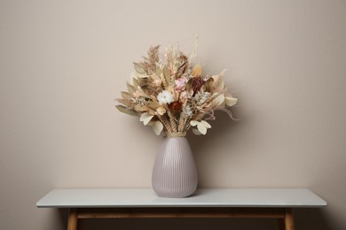 Photo of Beautiful dried flower bouquet in ceramic vase on white table near light grey wall