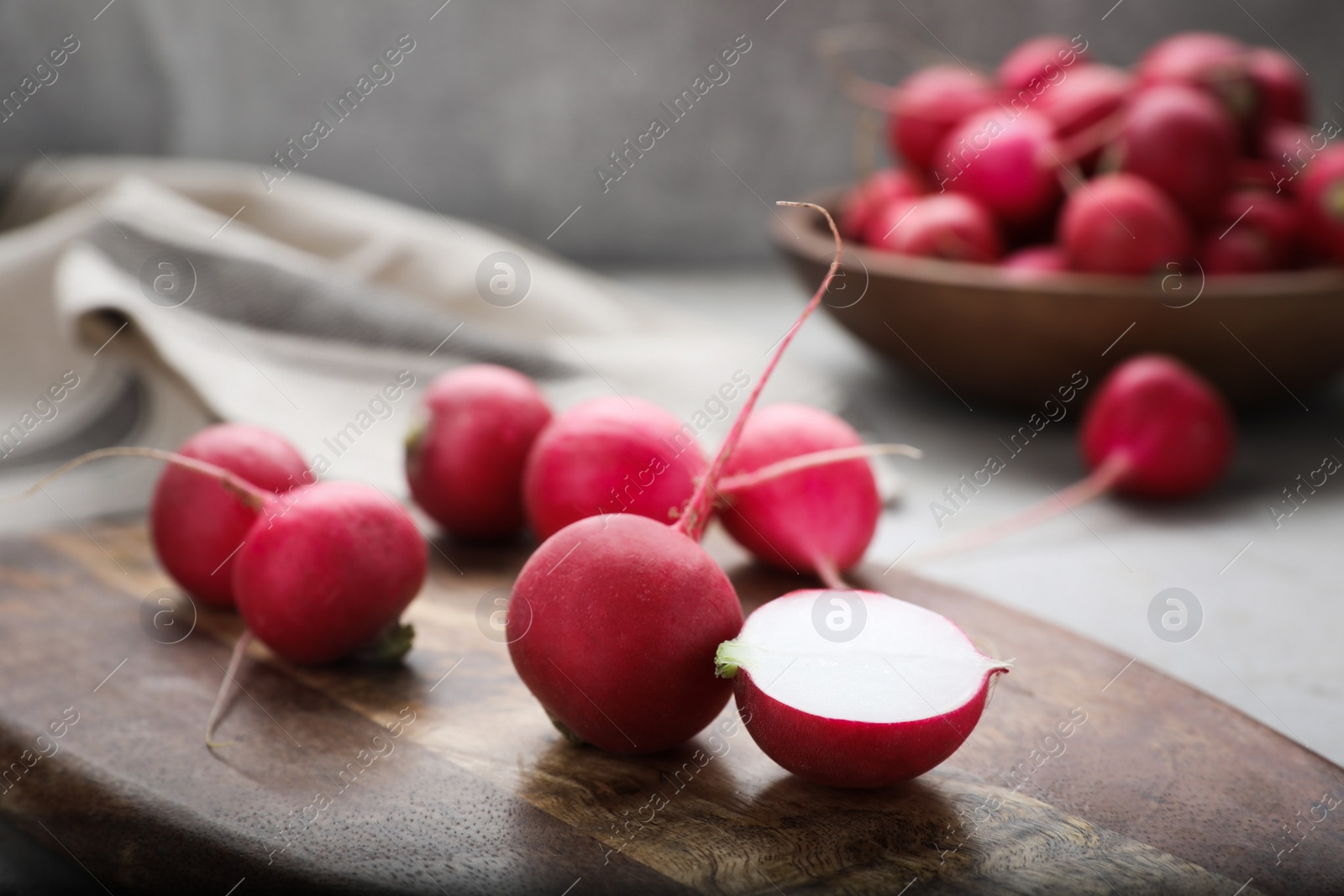 Photo of Wooden board with fresh ripe radishes on table, closeup