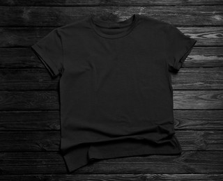 Stylish t-shirt on black wooden background, top view